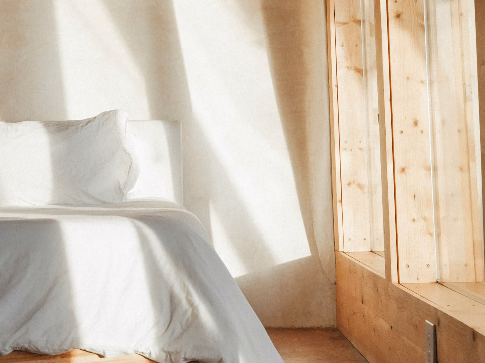 Un cuarto con la cama hecha y la luz de la tarde entrando por la ventana